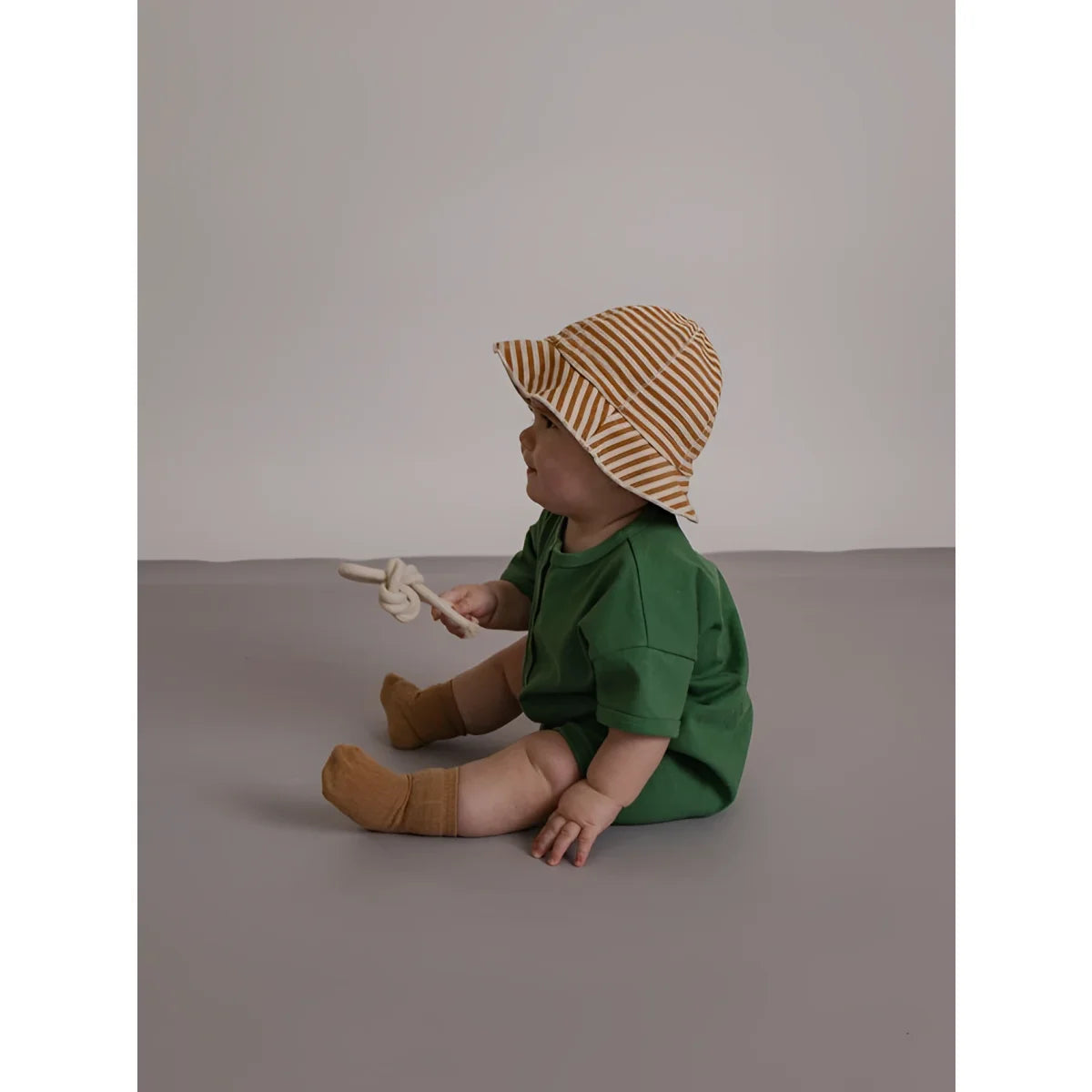 Ein baby trägt einen tan und beige gestreiften bucket hat zum romper seagrass beach aus leichtem material