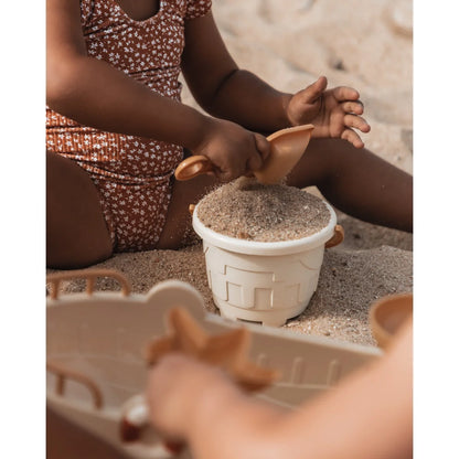Weißer Kunststoffeimer gefüllt mit Sand oder Körnern für Sandspielzeug Schiff
