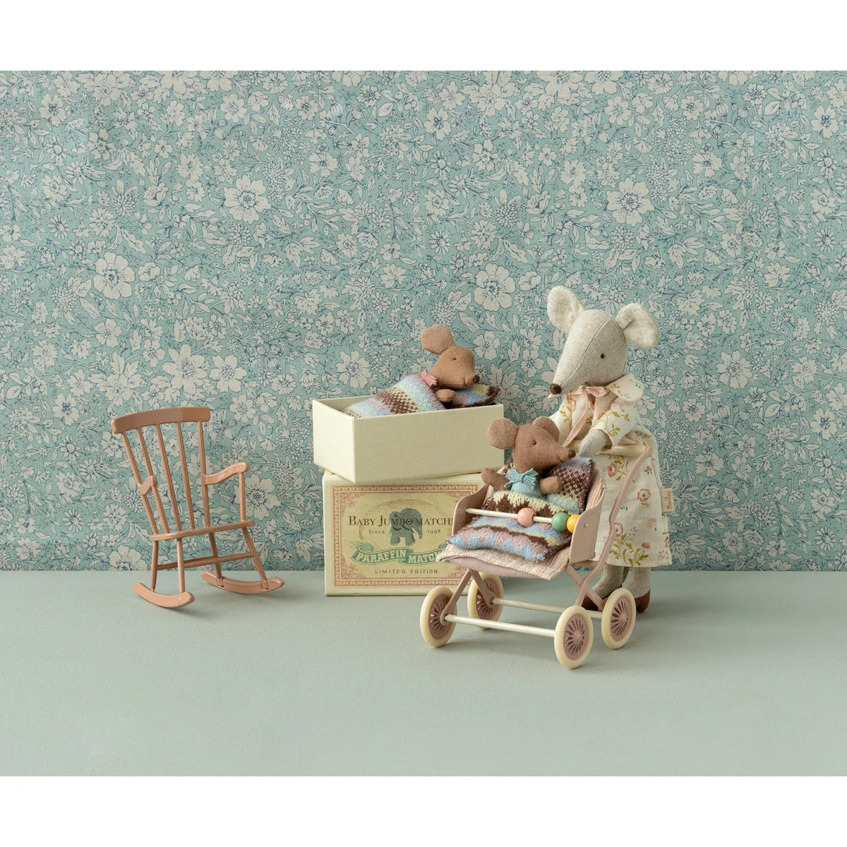 Gestopfte Maus spielt mit einem Holz-Babywagen und einem weiteren Spielzeug darin