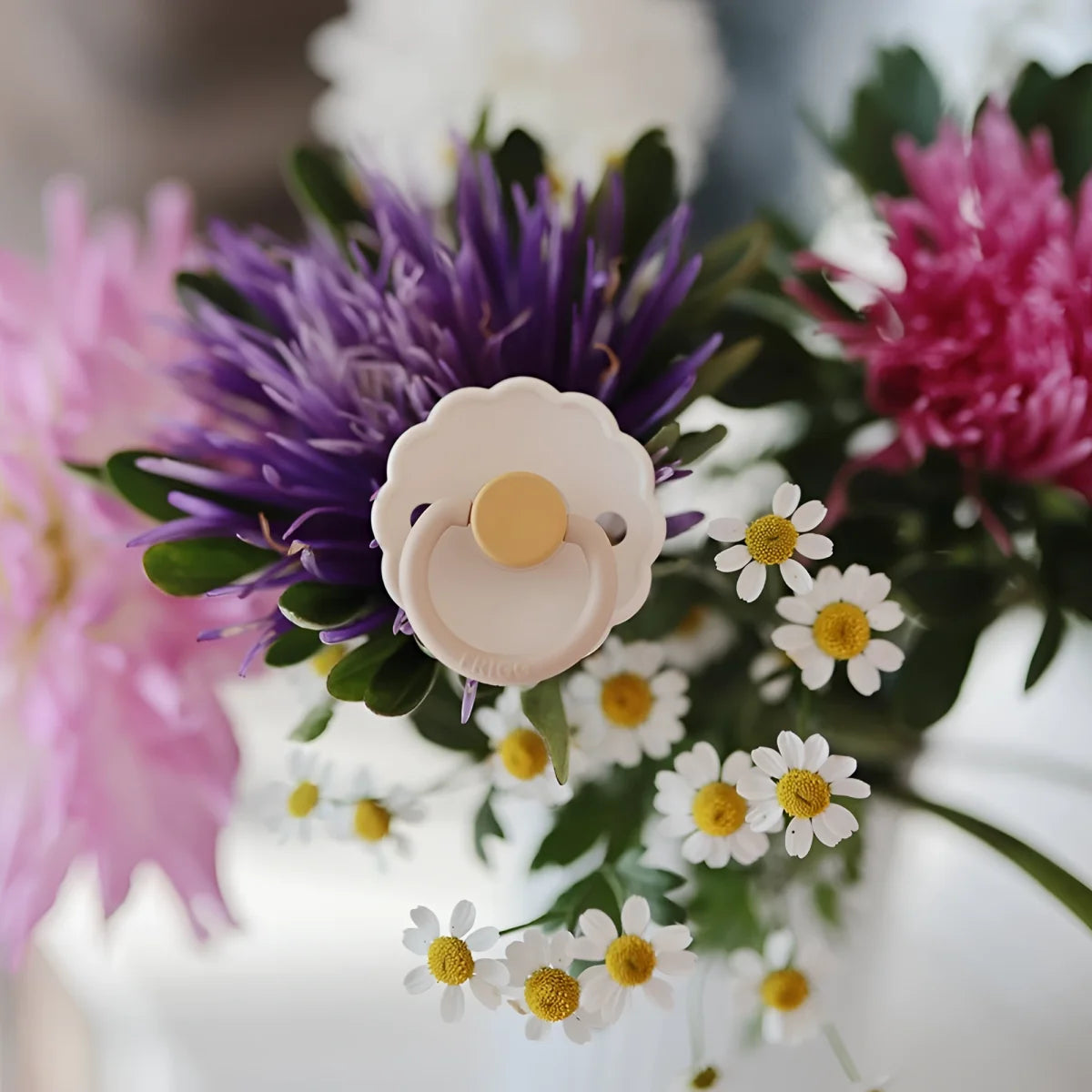 Ein creamfarbener schnuller latex mit gelbem sauger und wellenrand inmitten bunter blumen für geschenke für neugeborene