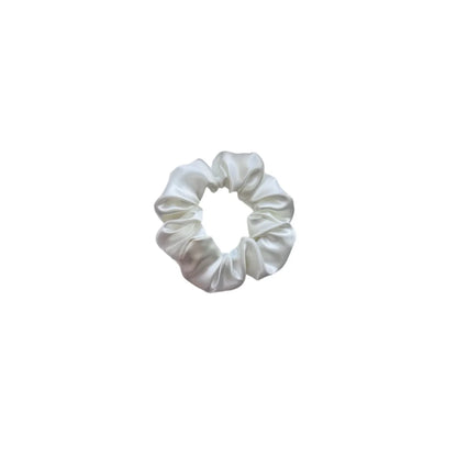 Ein elegantes weißes satin scrunchie mit glattem glänzendem finish und weicher geraffter textur von felice