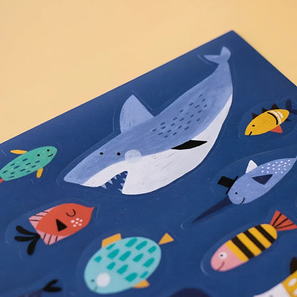 Bunte Illustration eines Wals und verschiedener Fische auf blauem Hintergrund für Sea Stickers