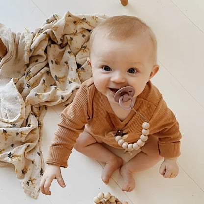 Lächelndes Baby mit Schnuller an Silikon Nuggikette aus Baumwolle