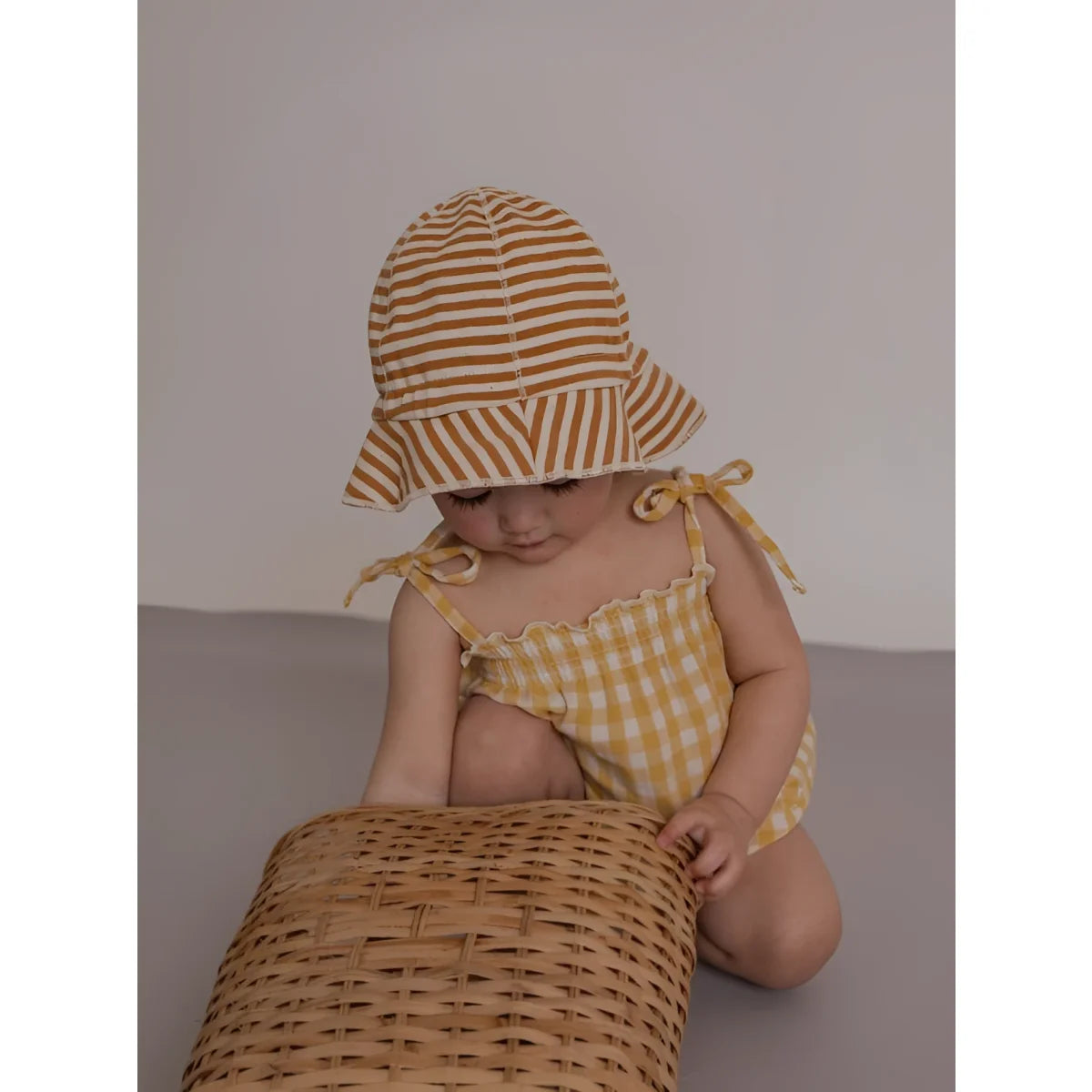 Baby in Spaghetti Bodysuit Honeycomb Gingham mit gelb-weiß gestreiftem Sonnenhut
