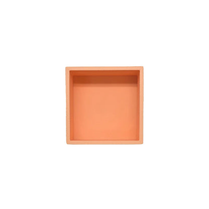 Ein quadratisches, pfirsichfarbenes keramikspielschälchen mandigo mit matter oberfläche und leicht erhöhten rand in orange