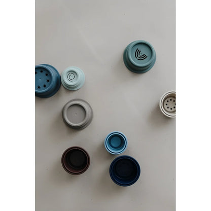 Sammlung von blauen, grauen und schwarzen Plastikflaschenverschlüssen im Stapelturm Forest