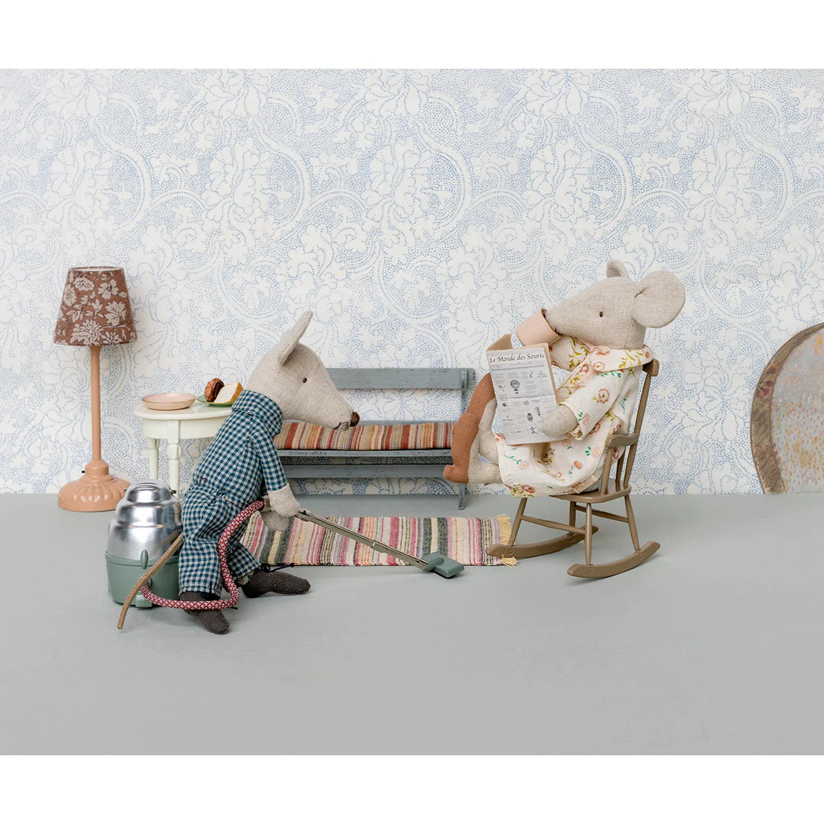 Zwei Stoffmaus-Spielzeuge in einer gemütlichen Leseecke mit einem Schaukelstuhl