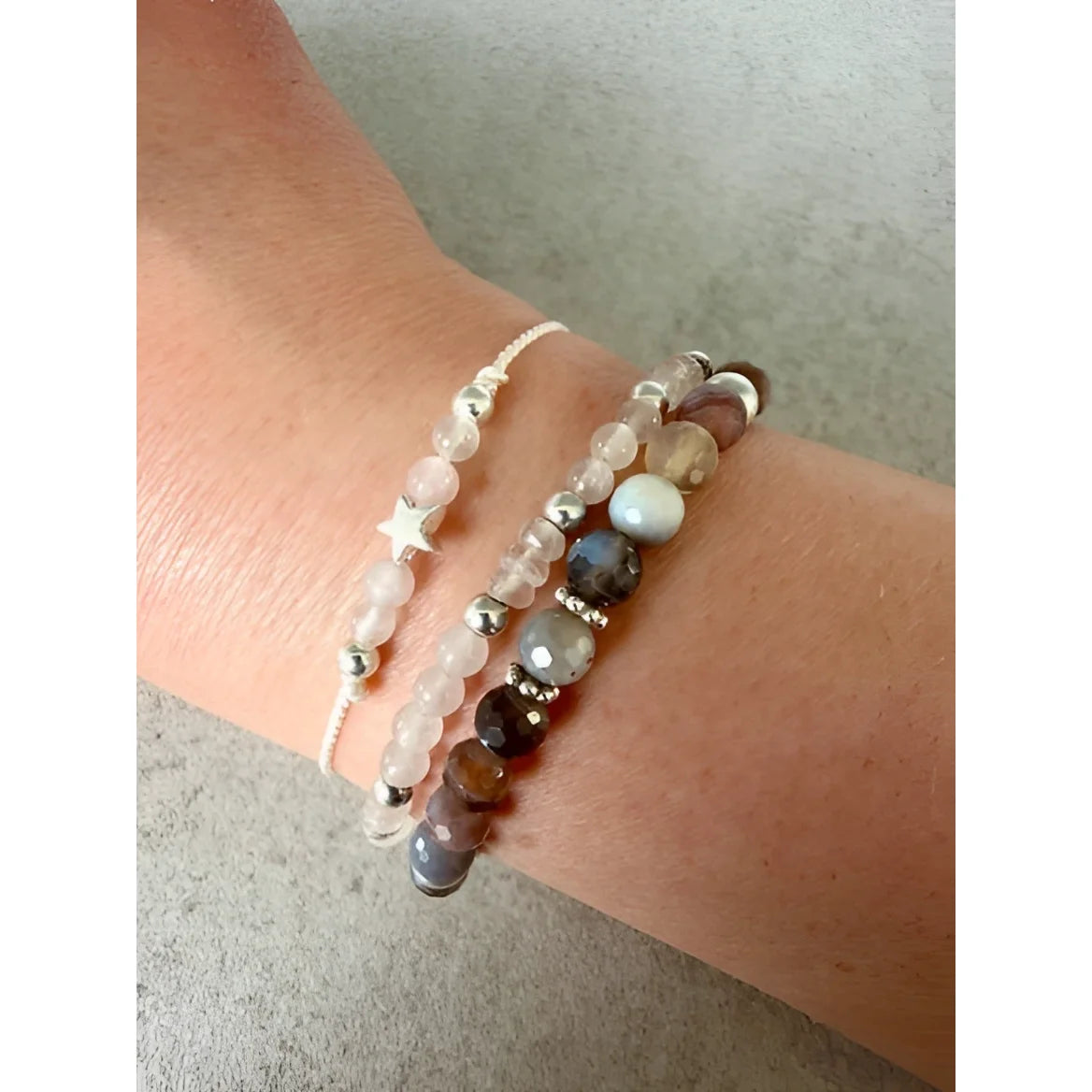 Ein weisses perlenarmband mit einem filigranen silbernen sternanhänger als nachhaltige geschenke für neugeborene