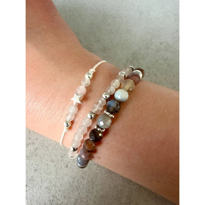 Ein weisses perlenarmband mit einem filigranen silbernen sternanhänger als nachhaltige geschenke für neugeborene