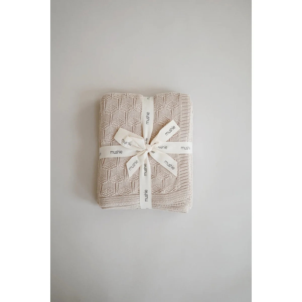 Gefaltete beige Strickdecke mit weißem Satinband, Honeycomb Beige