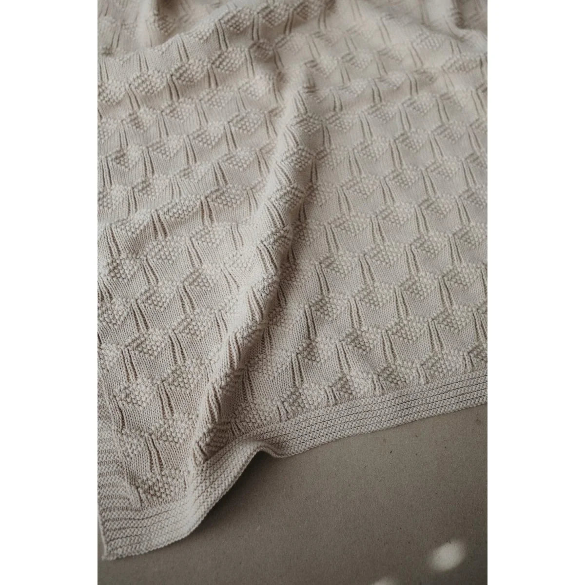 Cremefarbene Strickdecke mit einem strukturierten Rautenmuster in Honeycomb Beige