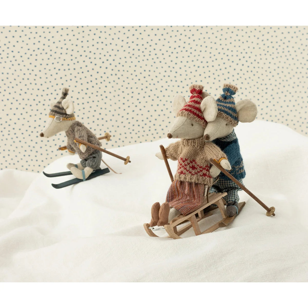 Drei Spielzeugmäuse beim Skifahren auf dem Strickpullover und Mütze von Mama Maus