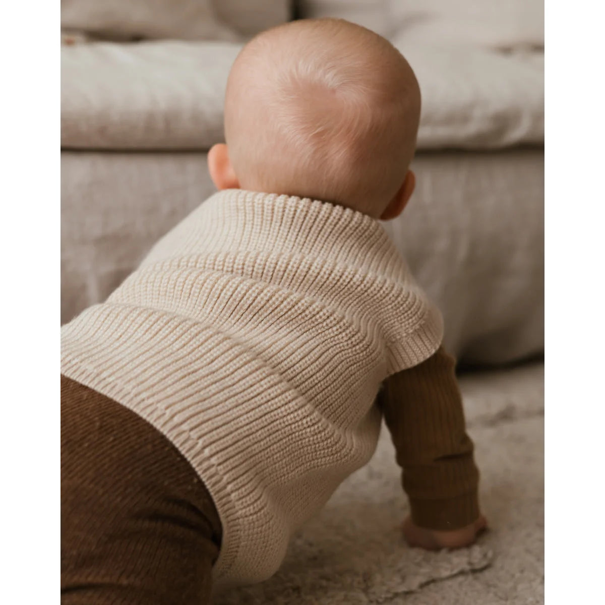 Baby in cream Strickpullunder Vest Harvey mit braunen Hosen gekleidet