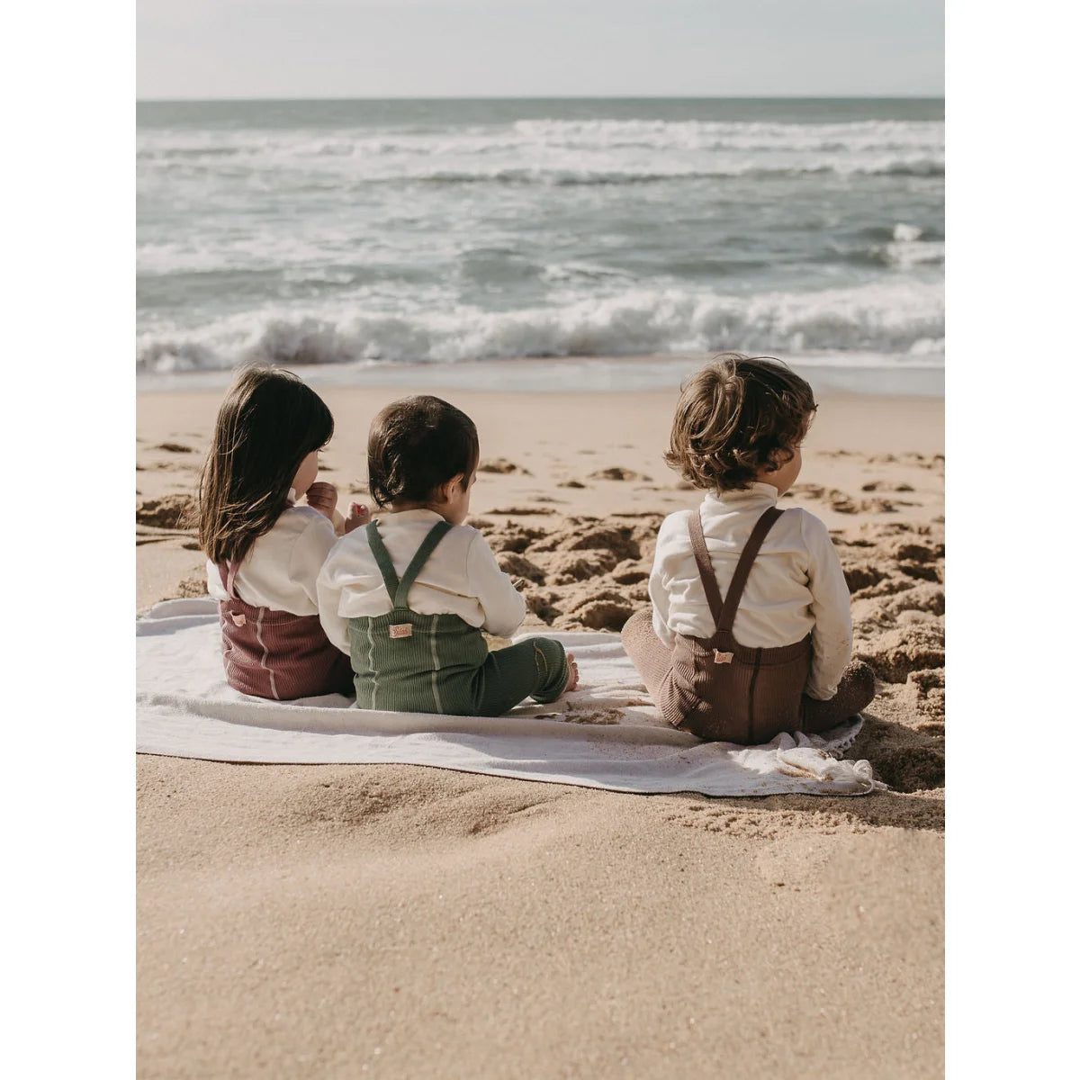 Drei Kinder auf einem Strandtuch, blickend auf den Ozean im Acai Smoothie Design