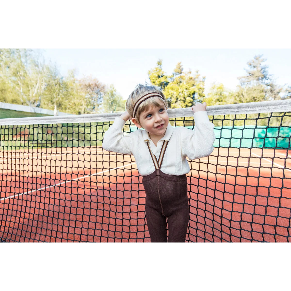 Kind im Vintage-Tennis-Outfit mit Strumpfhose mit Träger in Schokoladenbraun gestreift