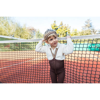 Kind im Vintage-Tennis-Outfit mit Strumpfhose mit Träger in Schokoladenbraun gestreift