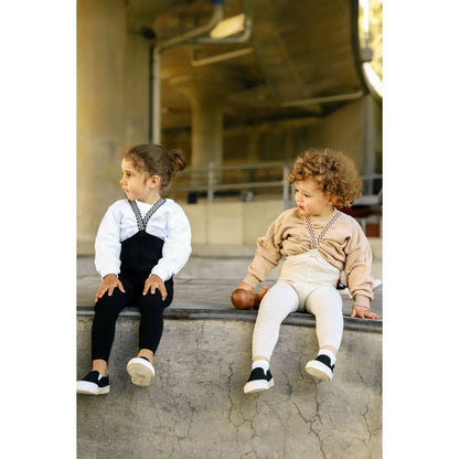 Zwei Kinder in passenden Outfits mit Strumpfhose mit Träger Footless im Karomuster