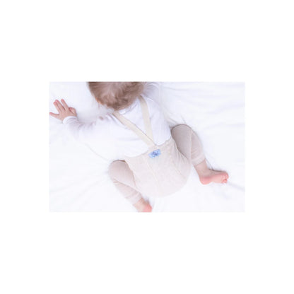 Baby im weißen Onesie auf hellem Untergrund, passend zu Strumpfhose mit Träger Footless