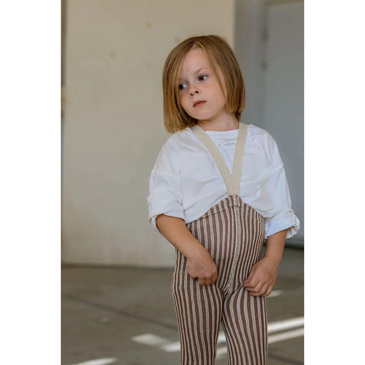 Kind mit weißem Hemd und Granola-Creme-Streifen-Overalls mit Trägern