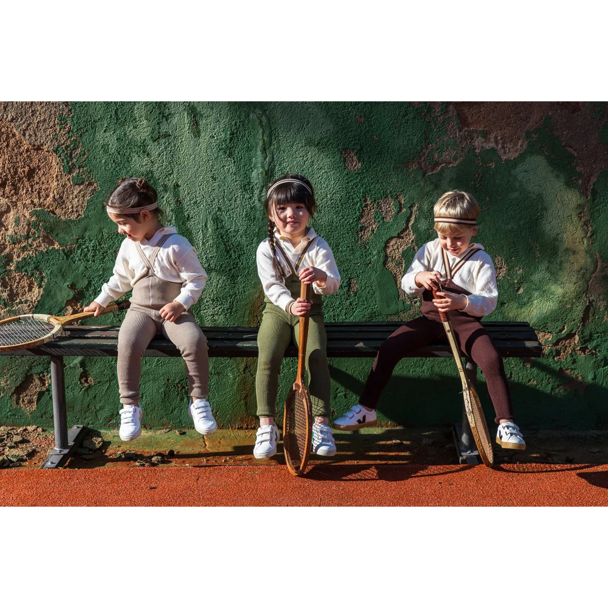 Drei Kinder mit Tennisschlägern neben Strumpfhose mit Träger Footless in Olive gestreift