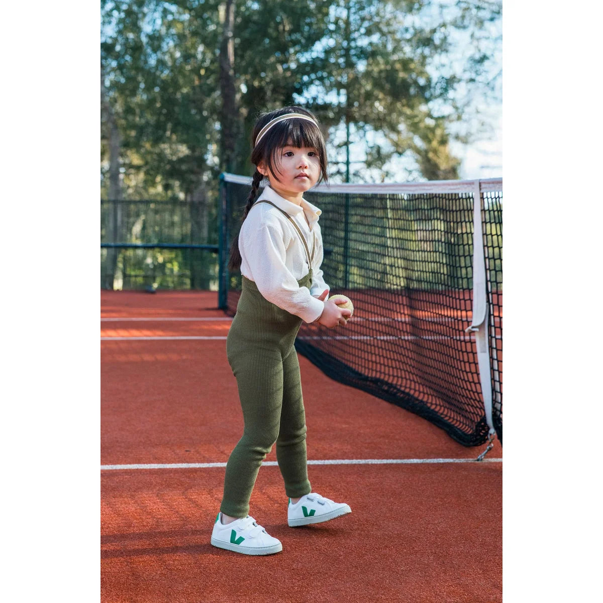 Junge Spielerin auf dem Tennisplatz trägt Olivgrüne Streifenstrumpfhosen ohne Fuß