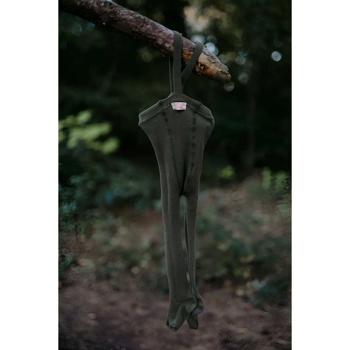 Dunkelgrüner Jumpsuit hängt an einem Baumast, präsentiert für Strumpfhose mit Träger Footed