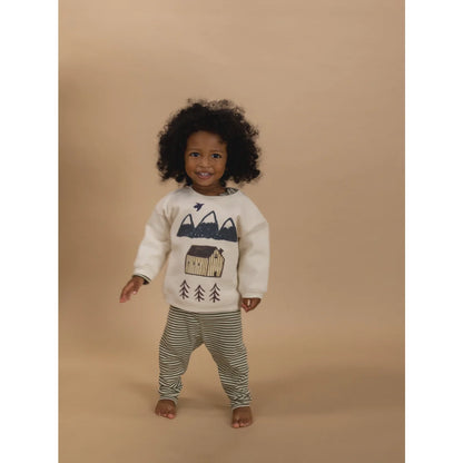 Lächelndes Kind trägt undyed Sweatshirt mit Cabin Adventure Grafik und gestreiften Hosen