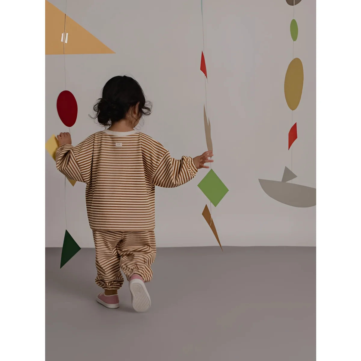 Kind trägt beige braun gestreiften sweatshirt mit passenden hosen aus weichem material copper stripes