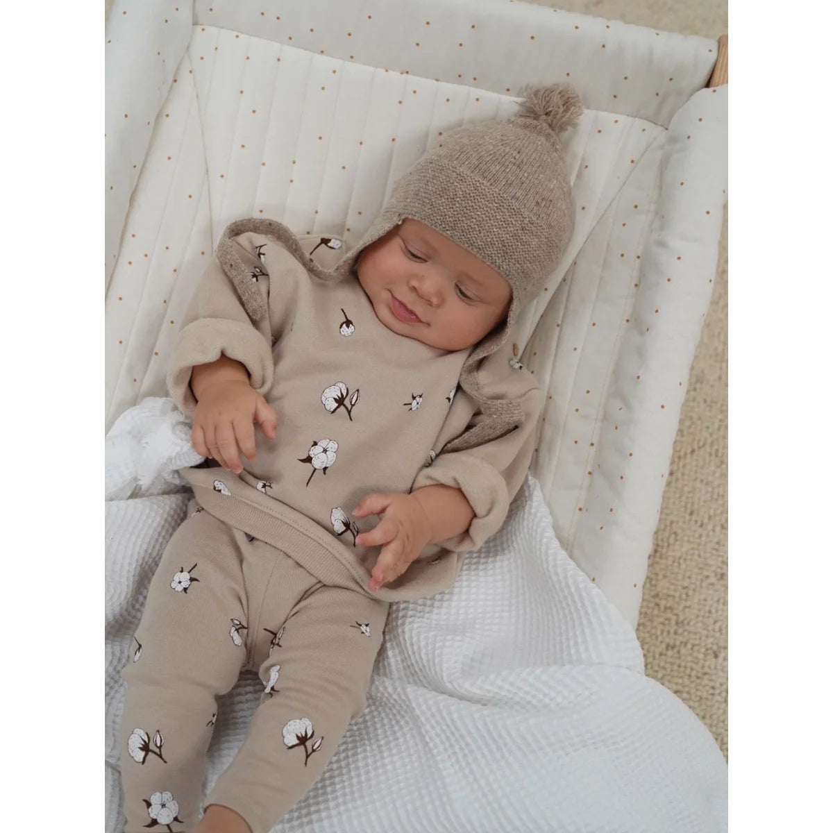 Schlafendes Baby in Strickmütze und floralen Overall, präsentiert mit Sweatshirt Cottonfield