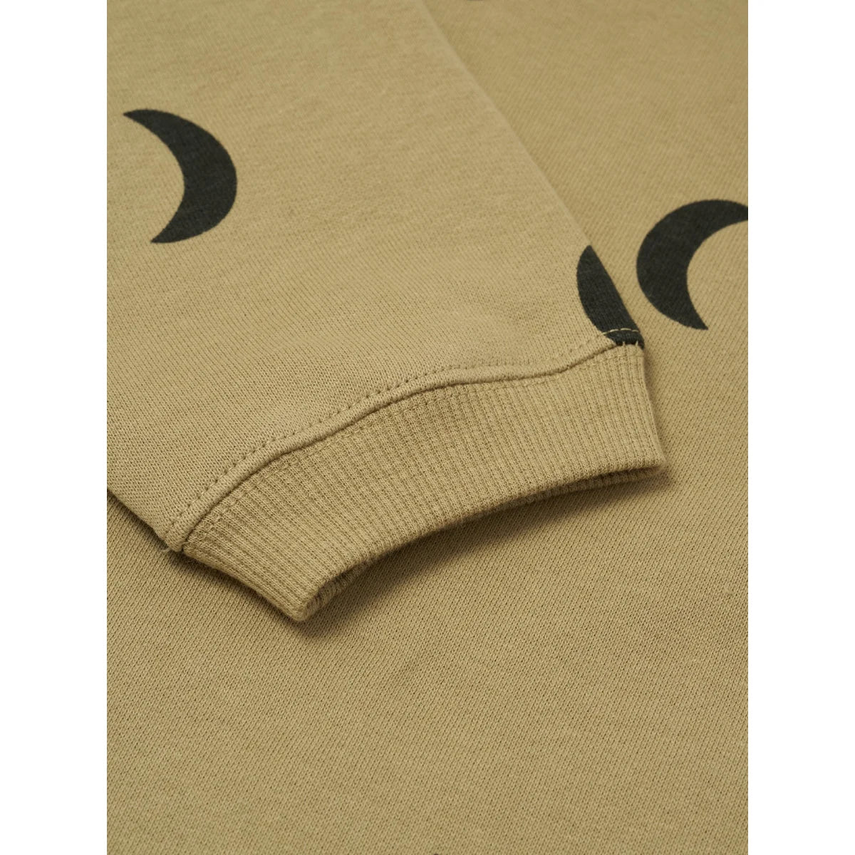 Nahaufnahme eines beigen Sweatshirtärmels mit schwarzen Halbmondmustern und Rippenbündchen