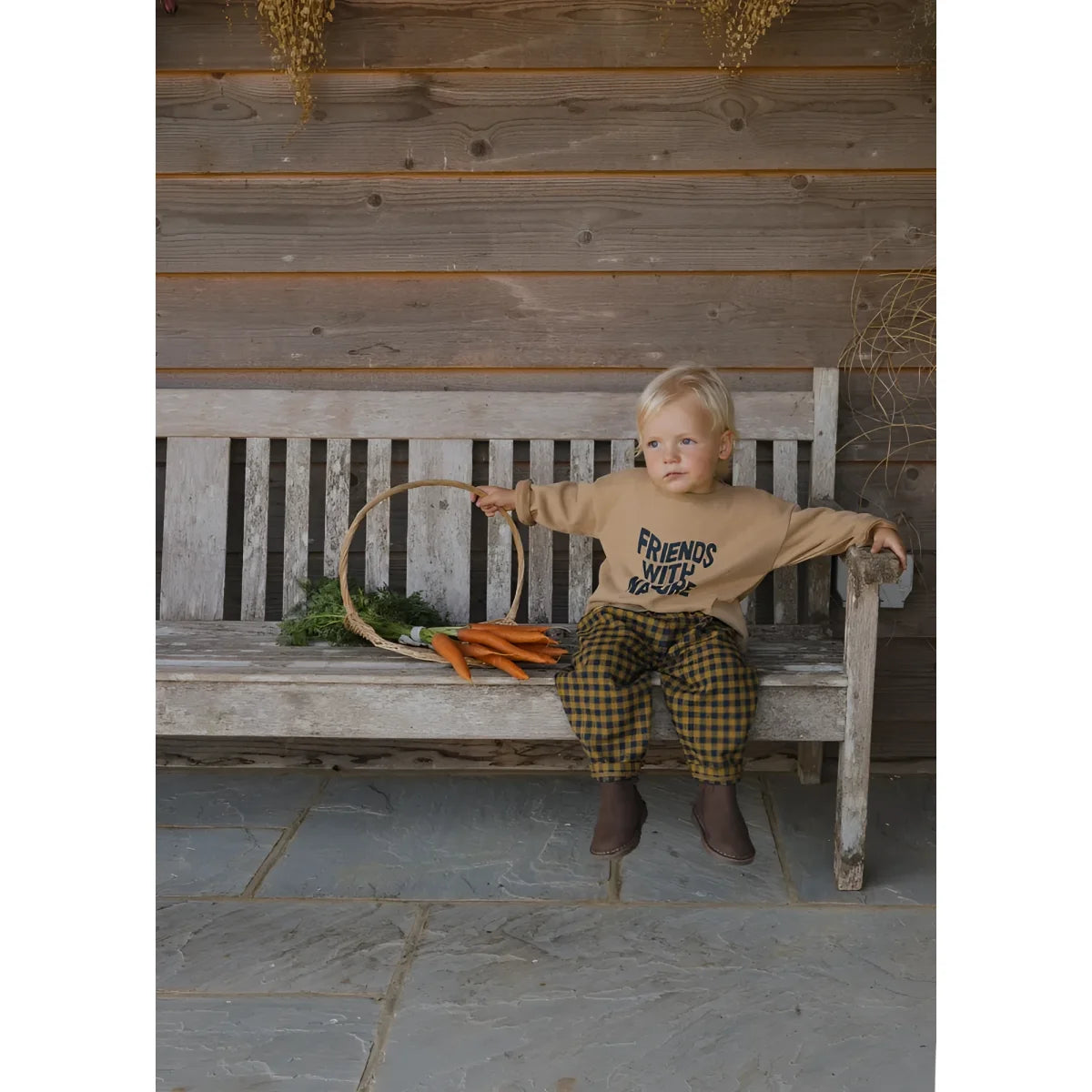 Wettered wooden bench with a child wearing the Friends with Nature sweatshirt