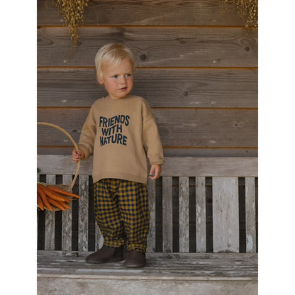 Ein Kleinkind trägt einen beigen Friends with Nature Sweatshirt und karierte Hose