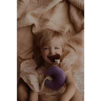 Lachendes Baby mit lila Stofftier auf Stoff, Produkt Teddy Mond | Purple Rain