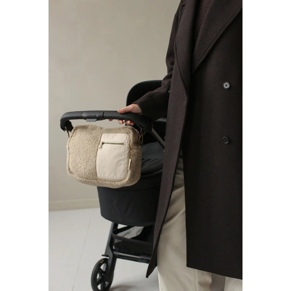 Beige Canvas Wickeltasche am Griff eines schwarzen Kinderwagens der Marke Teddy