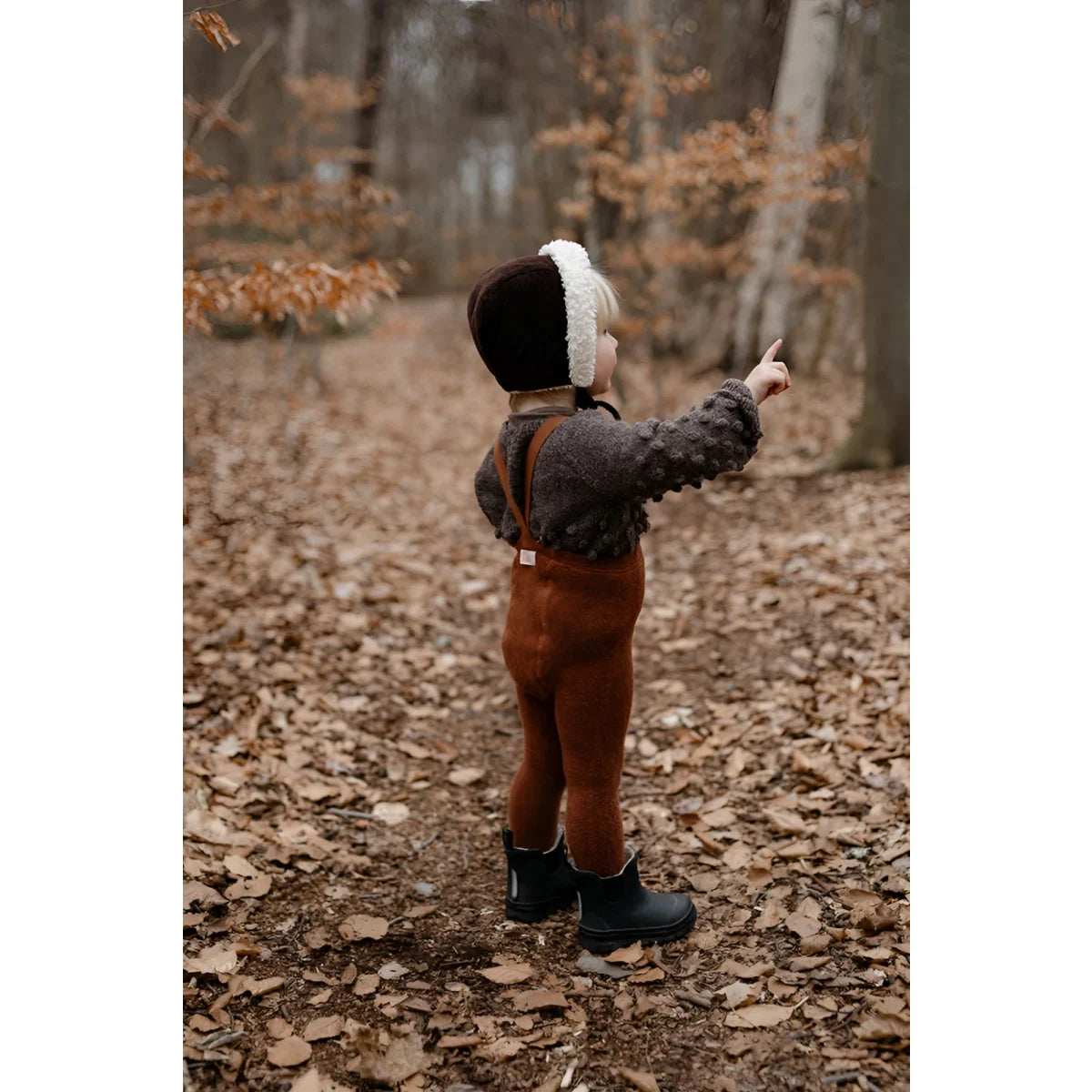 Kind in Mütze und Jacke im Wald mit Teddy Warmy Strumpfhose in Zimt
