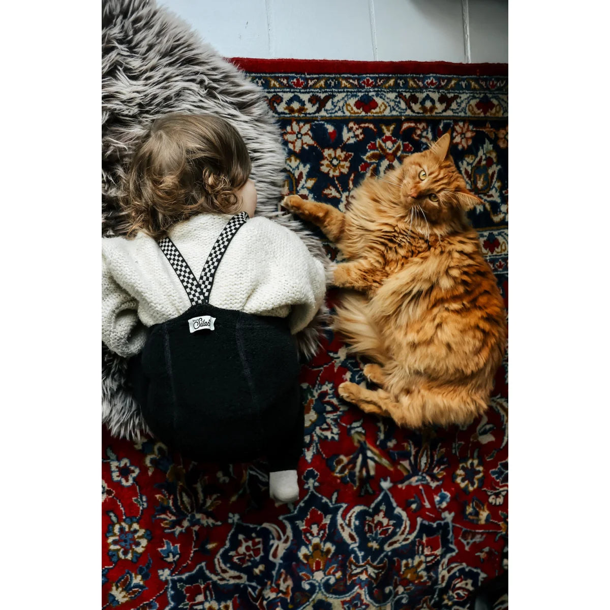 Baby und orange Katze auf einem Teppich mit Teddy Warmy Strumpfhose in Schwarz kariert