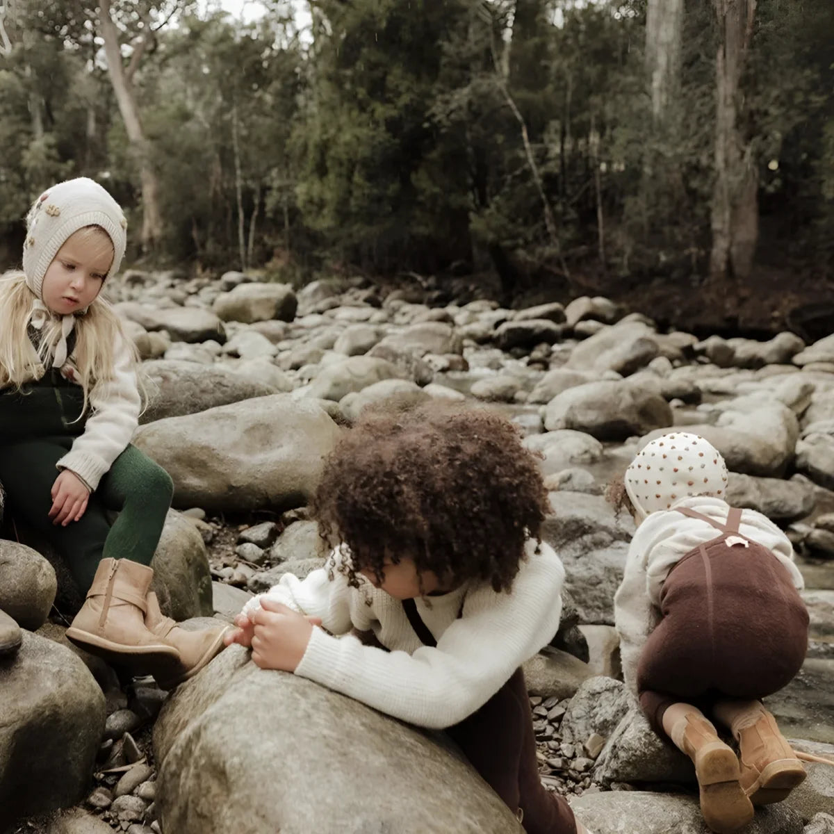 Drei Kinder sitzen auf Steinen in der Natur, tragen Teddy Warmy Strumpfhosen
