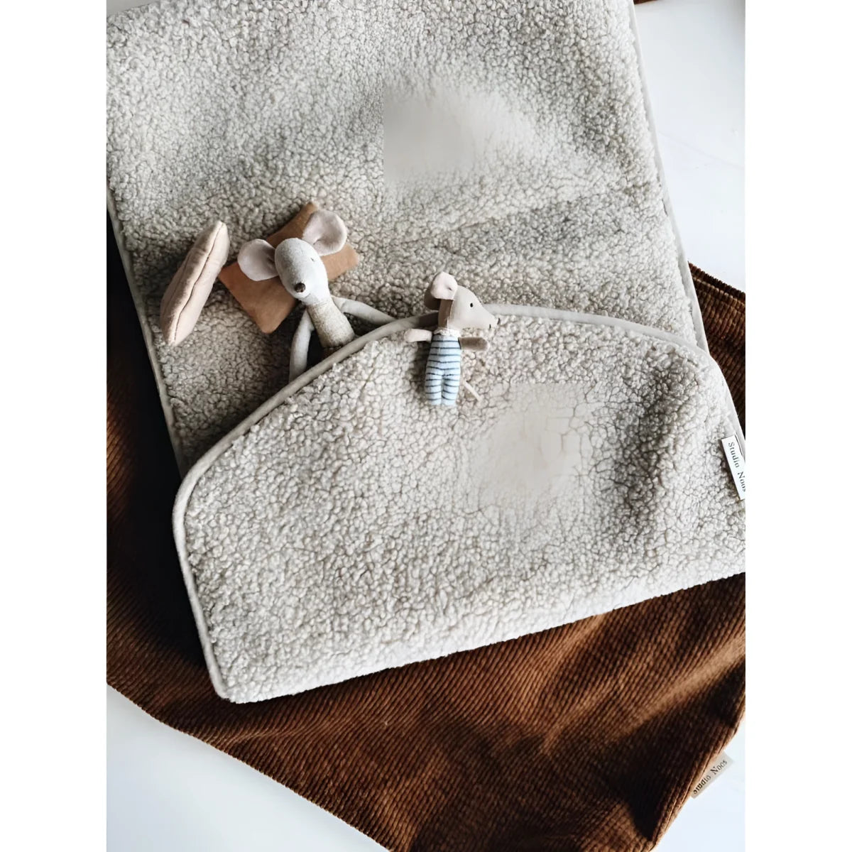 Weiches graues Handtuch mit kleinen Holzspielzeugen auf Teddy Wickelunterlage Ecru