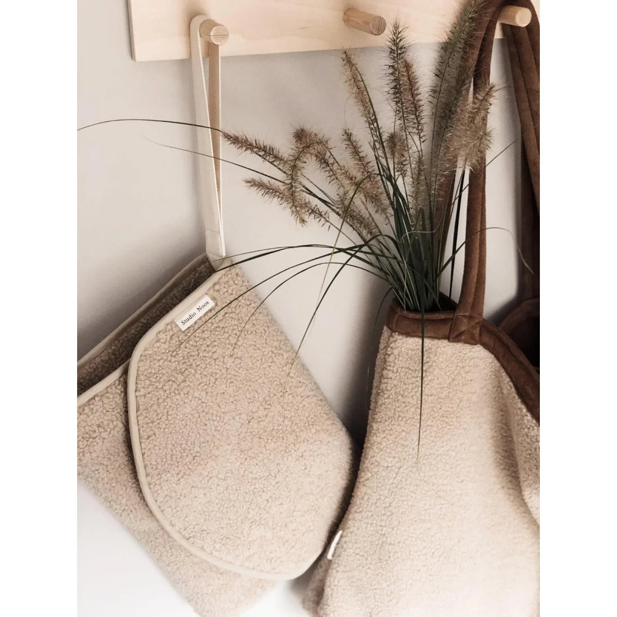Beige oder cremefarbene Ofenhandschuhe hängen an Haken neben Teddy Wickelunterlage Ecru