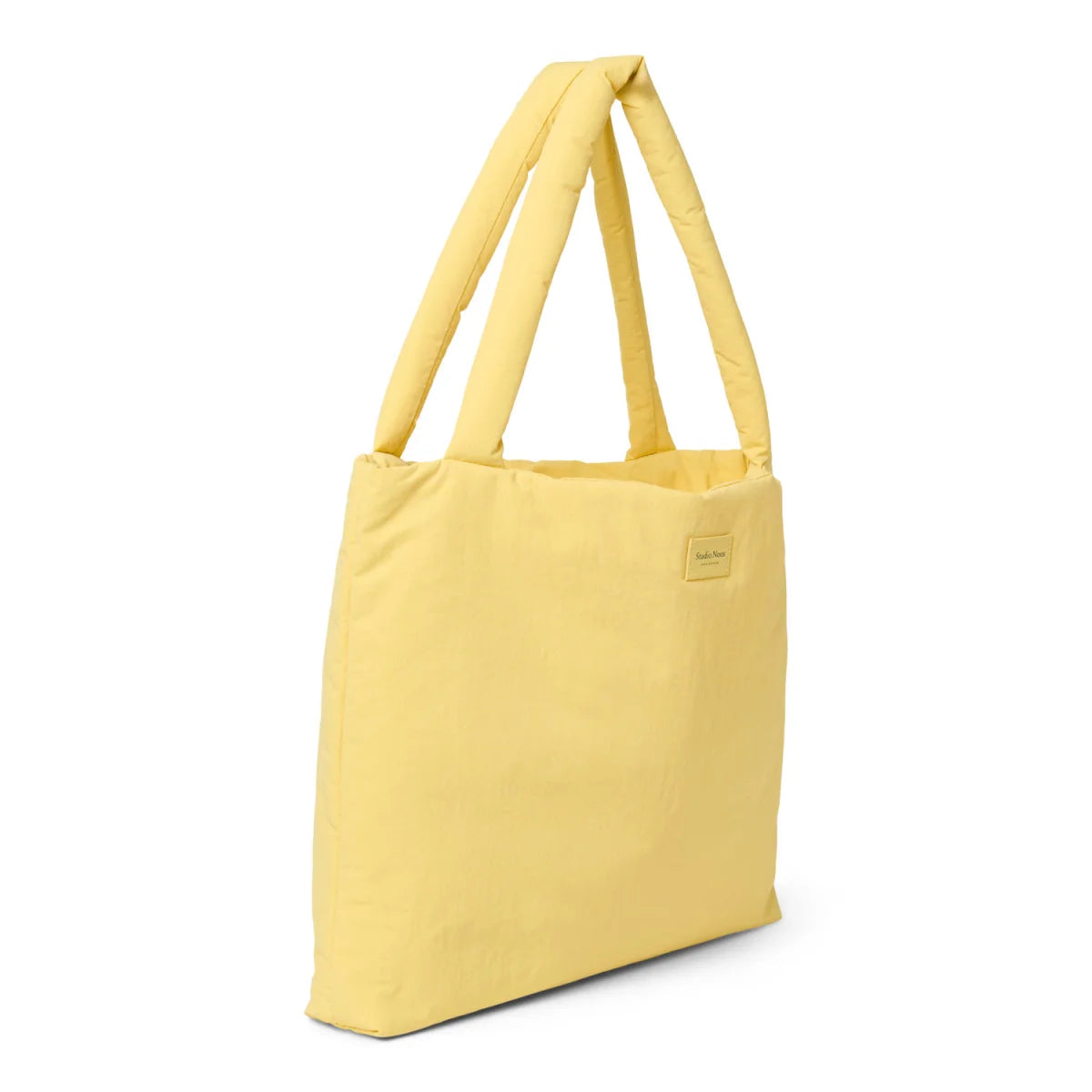 Weiches gelbes gesteppte mom bag mit gepolsterten griffen und kleinem goldfarbenem markenlogo