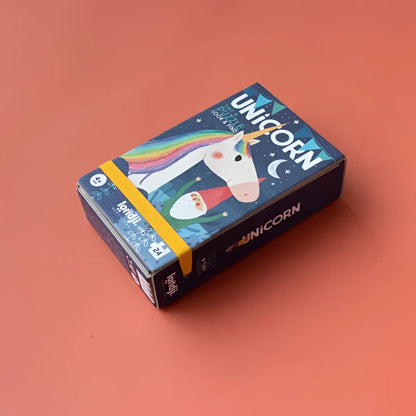 Blaue Kartonbox mit bunter Einhorn-Illustration und gelbem Band, beschriftet Unicorn Jigsaw Puzzle von Lonti für Unicorn Tiny