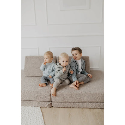 Drei junge Jungen in abgestimmten Outfits auf einem modularen Sofa, Unisex Oversized Hoodie Peace in weichem Grün