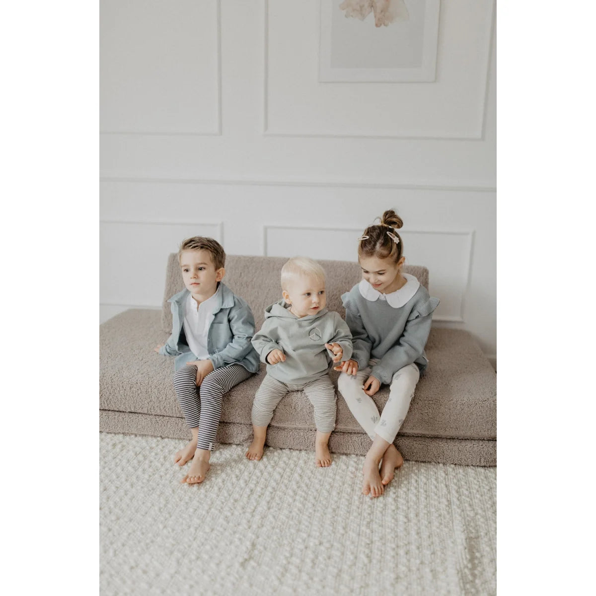 Drei junge Kinder sitzen barfuß auf einem Sofa in einem Unisex Oversized Hoodie Peace