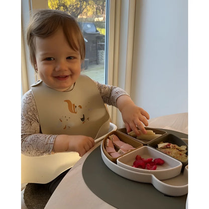 Ein Kleinkind mit Lätzchen sitzt an einem Tisch vor einem Unterteilter Arne Mr. Bear Teller