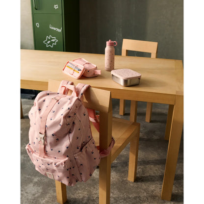 Pink rucksack mit schwarzem pfeilmuster hängt an einem holzstuhl neben wasserflasche falk 350 ml mini cherry heart rosey
