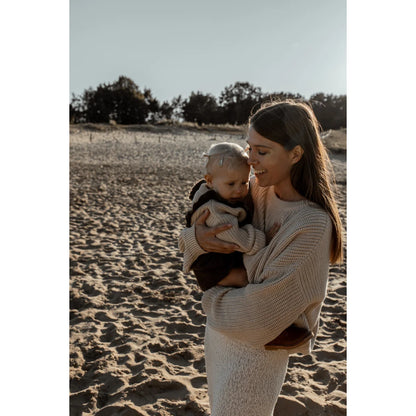 Frau hält ein Baby am Strand in einem Frauen Chunky Knit Sweater Oat