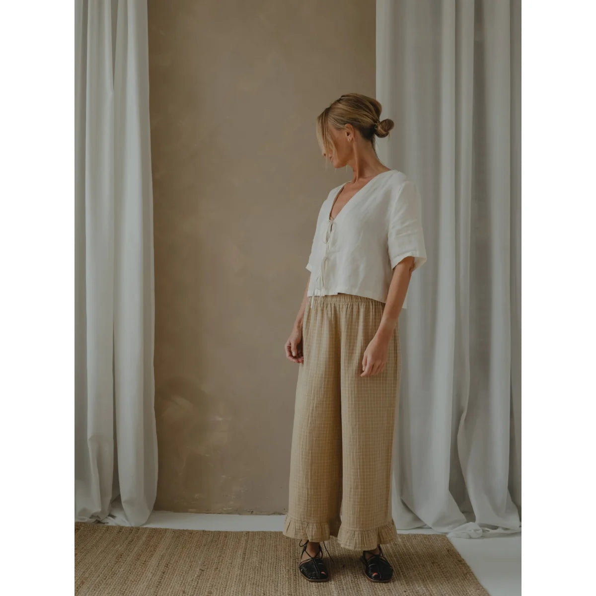 Frau trägt weiße Bluse und beigefarbene Culottes in Wheat Grid Check Frill Pants