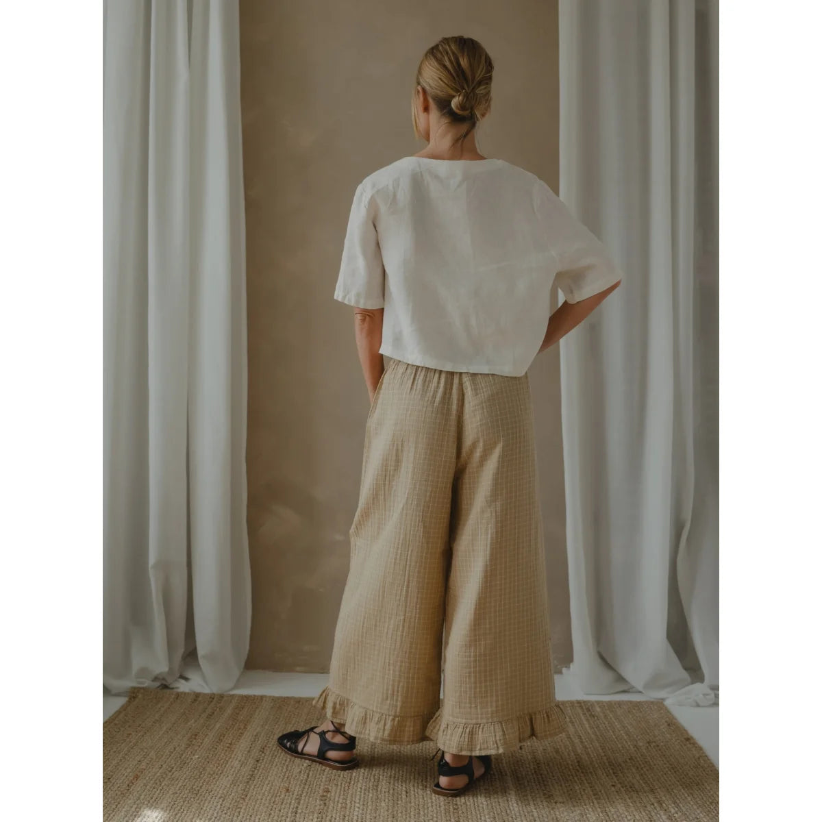 Frau trägt weiße Bluse und beigefarbene Culottes aus dem Wheat Grid Check Sortiment