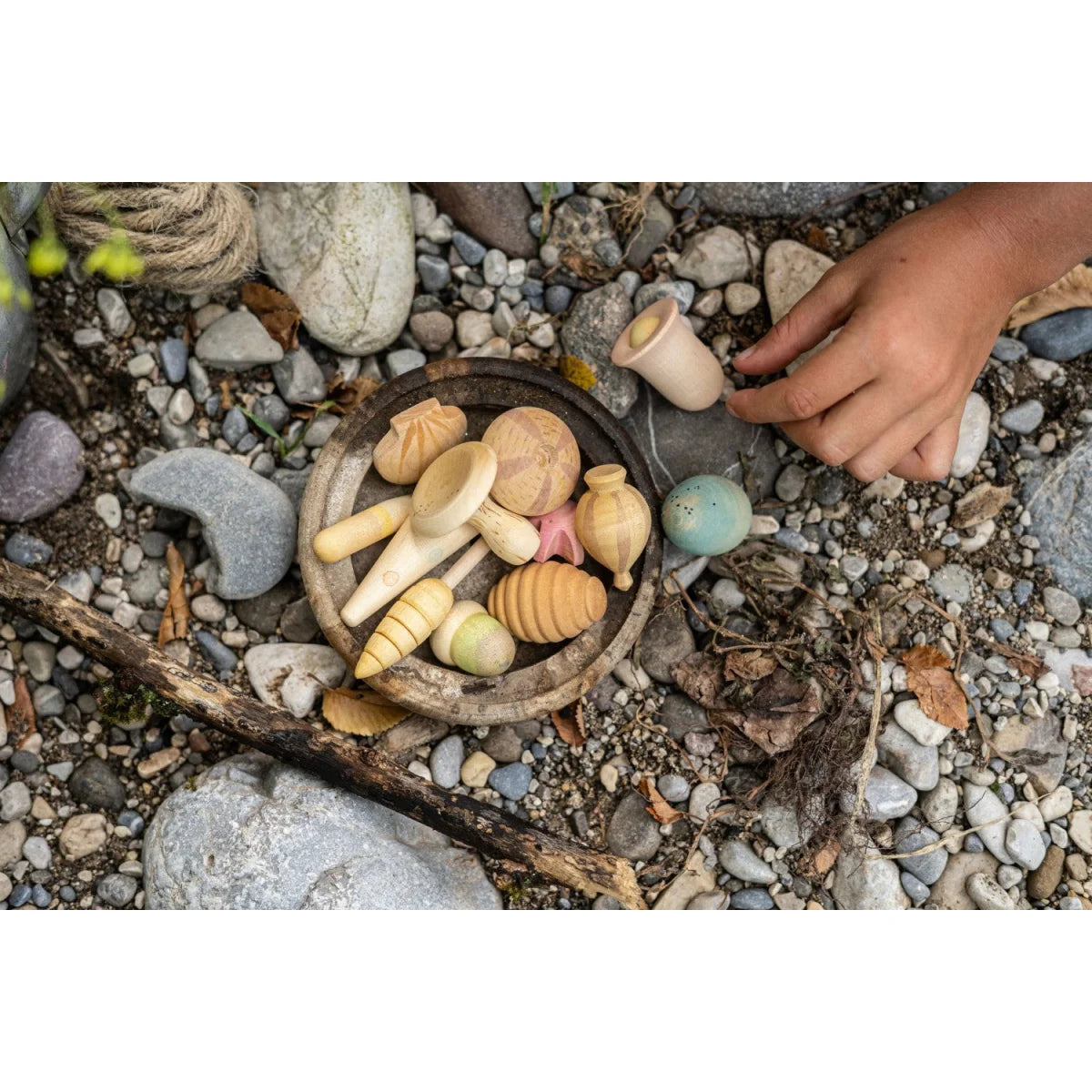 Holzschüssel mit natürlichen Holzspielzeugen und einem blau-grünen Keramik-Ei aus Wonders