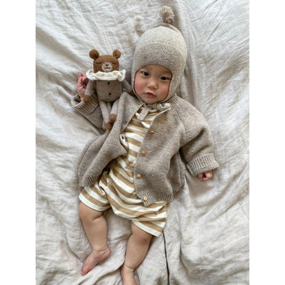 Süßer Säugling in Oatmeal Wollcardigan, Strampler und Bonnet hält Teddy